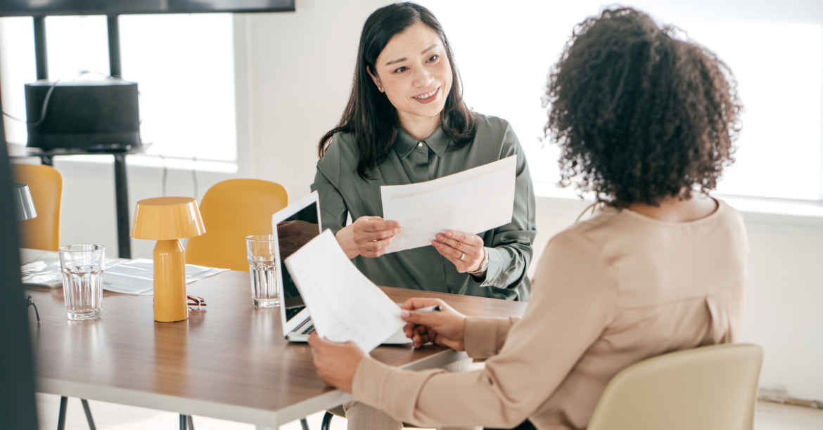 Photo of two women sitting at a table in an office setting.