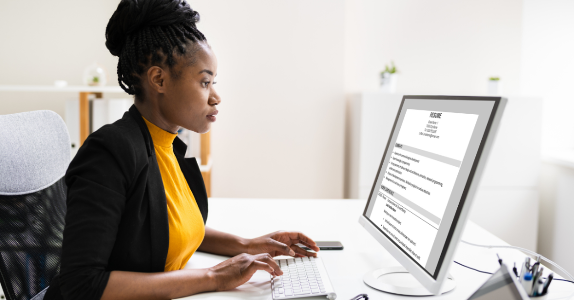 Black woman crafting her resume on a computer in an office