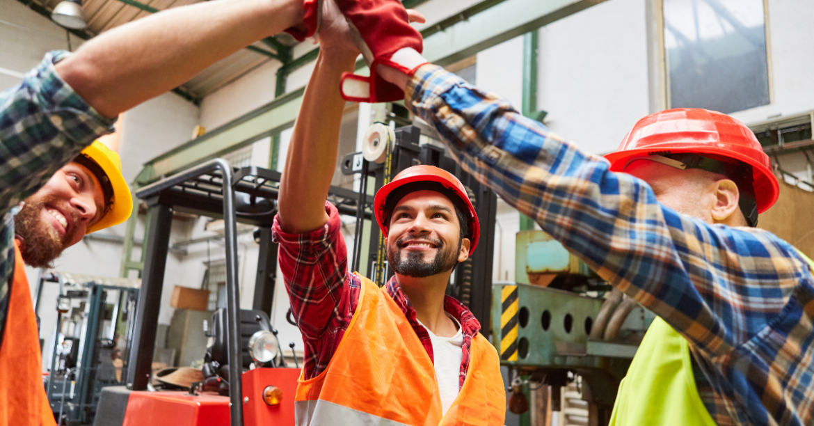 Three production men high-fiveing in a warehouse