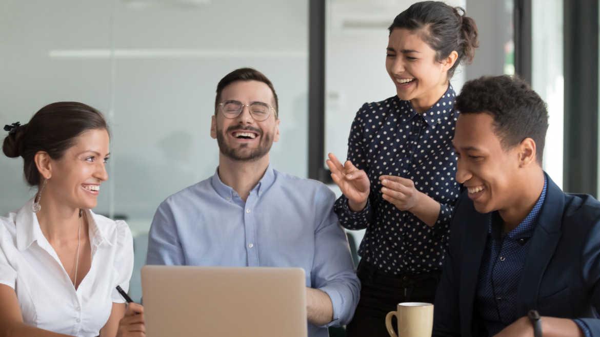 Four people laughing and having a good time while at work.